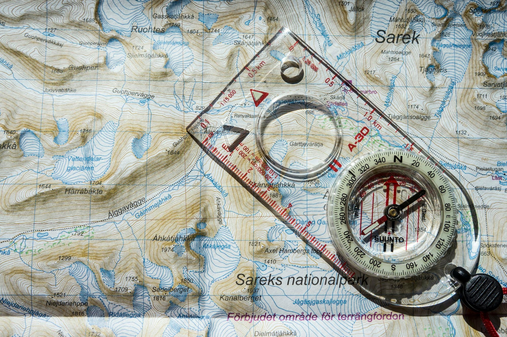 A transparent compass resting on a topographic map.